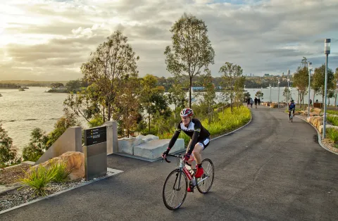 Man riding a bike along a bikepath in a city park.